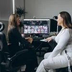 Two motion graphics designers discussing animation projects at a workstation with motion design work displayed on screen