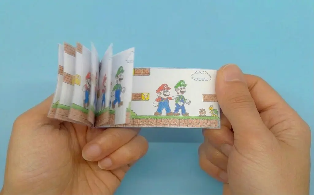 Hands flipping a Mario flipbook to show the historical origins of frame-by-frame animation techniques.
