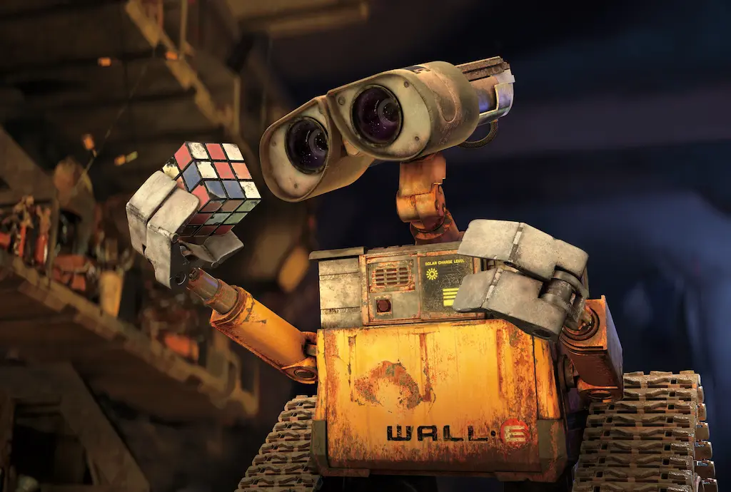 WALL-E holding a Rubik's cube in a cluttered workshop, illustrating environment staging and storytelling in animation.