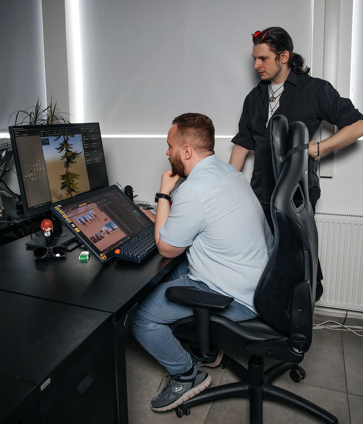 VSQUAD team members collaborating on a game art outsourcing pipeline: reviewing 3D environment assets and user interface for a console title on dual monitors, with a detailed workstation view.