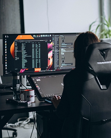 Professional game developer workspace with a dual monitor setup for cross-platform asset creation.